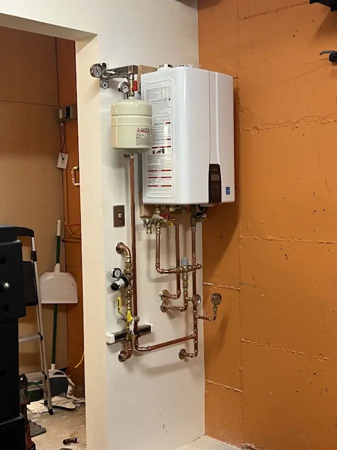 Plumbing technician inspecting water heater connections in Mahomet